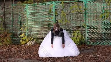 一个穿着婚纱的女孩，她的脸上有一个可怕的化妆在秋天。